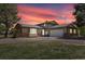 Inviting tan home with stone accents, two-car garage, mature trees, and gravel driveway at dusk at 1866 Mountain View St, Erie, CO 80516