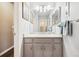 Bright bathroom with a gray vanity, white countertop, framed mirror, modern lighting and tiled shower through an open doorway at 4720 S Dudley St # 38, Littleton, CO 80123