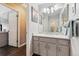 Well-lit bathroom featuring a gray vanity with a white countertop, framed mirror, and a doorway to an additional room at 4720 S Dudley St # 38, Littleton, CO 80123