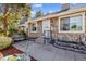 Home featuring stone siding, a landscaped yard with bench seating, and a white front door with black railings at 4720 S Dudley St # 38, Littleton, CO 80123