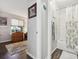 Hallway with wood floors leading to a bathroom with subway tile and a floral shower curtain, and a living room with natural light at 4720 S Dudley St # 38, Littleton, CO 80123