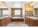 Bright bathroom with double sinks, cabinets, tile floor, and a soaking tub at 420 Graham Cir, Erie, CO 80516