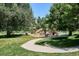A playground, complete with slides and climbing structures, set amidst a grassy area with mature trees at 5250 S Huron Way # 5-308, Littleton, CO 80120