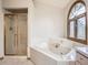 Bright main bathroom featuring a soaking tub with window and a shower with glass doors at 9670 W 69Th Ave, Arvada, CO 80004