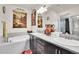 Bright bathroom featuring a tub, dual sinks with dark cabinets, and decorative accents at 3437 Rosato Dr # C, Highlands Ranch, CO 80126