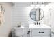 Modern bathroom featuring shiplap walls, a round mirror, and updated fixtures at 18233 E Dorado Ave, Centennial, CO 80015