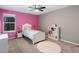 Charming bedroom with a pink accent wall, a cozy bed, and ample natural light from a large window at 18233 E Dorado Ave, Centennial, CO 80015