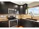 The kitchen has stainless steel appliances, dark cabinets, granite countertops, and a view from the window at 3720 Pecos Trl, Castle Rock, CO 80109