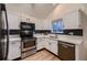 White kitchen with stainless steel appliances and dark tile backsplash at 2697 S Deframe Cir, Lakewood, CO 80228