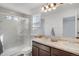 Bathroom featuring a tiled shower and double vanity with dark-stained cabinets and granite countertops at 17838 E 54 Th Ave, Denver, CO 80249