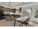Cozy dining room featuring sleek black table, seating for six, and access to kitchen at 17838 E 54 Th Ave, Denver, CO 80249