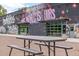 A picnic table in front of a building with mural, 'The World is Ours,' and unique garage doors at 3055 N York St, Denver, CO 80205