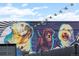 A brick building with a mural of three dogs, accented by string lights, creating a lively urban atmosphere at 3055 N York St, Denver, CO 80205