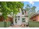 Charming back exterior featuring a grill, small patio, green fence, and nearby brick home at 3055 N York St, Denver, CO 80205