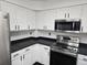 Modern kitchen featuring white cabinets, stainless steel appliances, and black countertops at 84 S Carlton St, Castle Rock, CO 80104