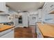 Open kitchen features stainless appliances, white cabinetry, wood counters, and hardwood floors at 5675 S Crocker St, Littleton, CO 80120