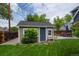 A backyard shed on a well-manicured lawn. There is a gray door, window and adjacent patio with seating at 5675 S Crocker St, Littleton, CO 80120