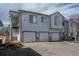 Three-unit townhouse with three garage bays and neutral gray paint with stone accents at 3242 E 103Rd Dr # 602, Thornton, CO 80229