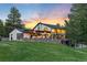Stunning exterior view of home with stone accents, outdoor seating area, and lush green lawn at sunset at 347 S White Tail Dr, Franktown, CO 80116