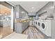 Well-equipped laundry room with ample storage, gray cabinets, and multiple washing machines and dryers at 347 S White Tail Dr, Franktown, CO 80116