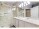 Bright bathroom featuring double sinks, white cabinetry, marble tile, and glass shower door at 13535 W 62Nd Ln, Arvada, CO 80004