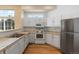 A classic kitchen with white cabinetry and stainless steel appliances, a tiled countertop, and hardwood floors at 13535 W 62Nd Ln, Arvada, CO 80004