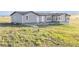 Backyard with grass leading up to home with daylight basement and gray exterior at 11100 Haskell Creek Rd, Larkspur, CO 80118