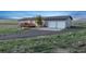 Single story gray house with a wood deck, two-car garage, and lawn at 11100 Haskell Creek Rd, Larkspur, CO 80118