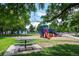 A charming playground with colorful equipment, surrounded by lush greenery and a picnic table, inviting for outdoor recreation at 4157 Perry St, Denver, CO 80212