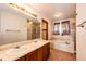 Well-lit bathroom featuring a double sink vanity, large mirror, soaking tub, and separate glass shower at 12842 Bellaire St, Thornton, CO 80241