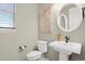 Bathroom features a pedestal sink, round mirror, and neutral paint at 30 S Ider Way, Aurora, CO 80018