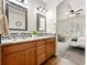 Bright bathroom featuring wood vanity, granite countertops, patterned backsplash, and an adjoining bedroom at 5836 S Vivian Way, Littleton, CO 80127