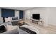 Comfortable basement living room with a cozy gray sofa, modern entertainment center, and access to other areas at 3379 W Wagon Trail Dr, Englewood, CO 80110