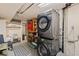 Functional basement laundry room with stacked washer and dryer, shelving, and ample storage space at 3379 W Wagon Trail Dr, Englewood, CO 80110
