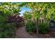 Lush backyard with a gravel path, mature trees, and vibrant flowerbeds at 3240 Spruce St, Denver, CO 80238