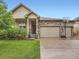 Charming home featuring a well-manicured lawn, a two-car garage, and stylish stone accents at 22466 E Layton Cir, Aurora, CO 80015
