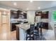 Modern kitchen island with granite countertops, bar stools, and dark wood cabinets at 22466 E Layton Cir, Aurora, CO 80015