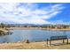 Picturesque lake view with a bench, showcasing clear water and mountains in the distance under a bright, cloud-filled sky at 11274 W 54Th Ln, Arvada, CO 80002