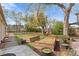 Manicured backyard with raised garden beds, a mature tree, and a patio with chairs at 3198 W Amherst Ave, Denver, CO 80236