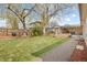 Large, well-maintained backyard with mature trees, patio, raised garden beds and green grass at 3198 W Amherst Ave, Denver, CO 80236