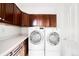 This laundry room includes a washer, dryer and overhead cabinets for storage at 6032 Umber St, Arvada, CO 80403