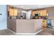 Cozy kitchen area featuring wooden cabinets, stainless steel appliances, and a bar-style counter at 13664 Linden Ct, Thornton, CO 80602