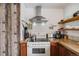 Close up of kitchen stove with stainless steel range hood and open wood shelves at 3200 Eastman Ave, Boulder, CO 80305