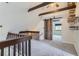 Loft area with wooden beams, carpet, and a modern barn door leading to another room at 11155 Kennedy Ave, Conifer, CO 80433