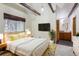 Stylishly decorated main bedroom with en-suite bathroom, wooden beams, and a large window at 11155 Kennedy Ave, Conifer, CO 80433