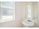 Bright bathroom with a pedestal sink, mirror, and a window providing natural light at 20108 Randolph Pl, Denver, CO 80249