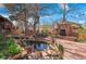 An inviting backyard features a stone fireplace, pond, and mature trees creating a serene outdoor oasis at 11545 Quivas Way, Westminster, CO 80234
