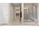 Neutral bathroom features a glass-enclosed shower with a bench, complemented by tile flooring and a peek into the closet at 16685 E 101St Ave, Commerce City, CO 80022