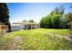 Large backyard with lush green lawn, storage shed, and mature trees offering shade and privacy at 1183 S Umatilla St, Denver, CO 80223