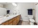 Bathroom with double sinks, wood cabinets, stone countertops, and a large mirror at 7375 S Alkire St # 102, Littleton, CO 80127